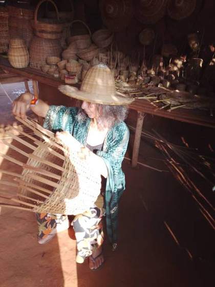 Artisane tressant un panier en osier, marché local
